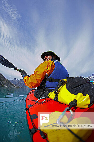 man traveling on a sea-kayak though the fjords of eastern Greenland