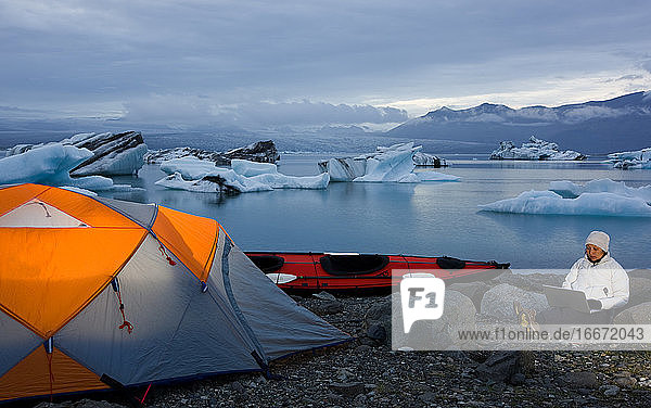 Frau benutzt ihren Laptop auf einem Campingplatz an der Gletscherlagune