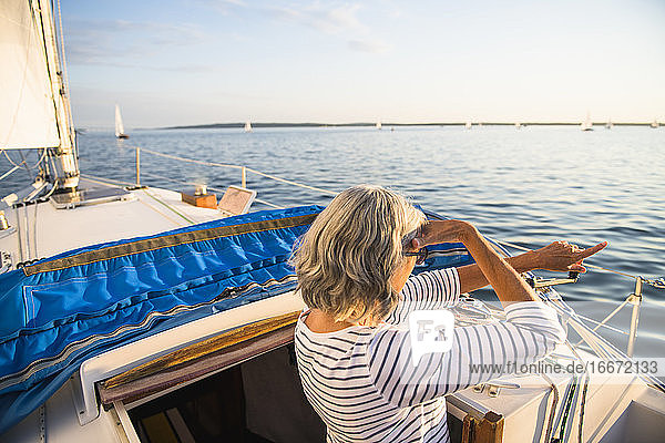 Middle age woman pointing during summer sail golden hour