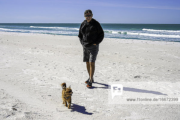 Mann und sein Hund machen einen Strandspaziergang