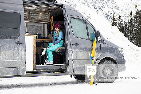 Eine Frau plaudert mit ihrem Hund  während sie sich für einen Skitag fertig macht.