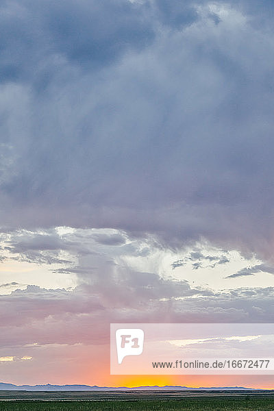 Glühender Sonnenuntergang  der die Horizontlinie über einem Feld in Meadow  Utah  berührt.
