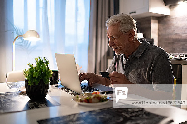 Älterer Mann benutzt Laptop zum Online-Shopping
