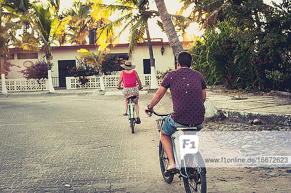 Mann und Frau fahren Fahrrad in einer tropischen ländlichen Stadt
