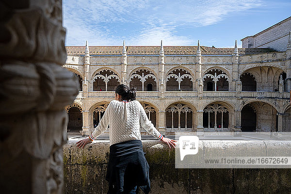 Rückansicht einer Frau  die auf einem Balkon vor einem alten Gebäude steht
