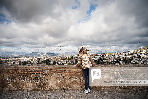 Mädchen schaut auf Granada Spanien mit Wind und dramatischen Wolken