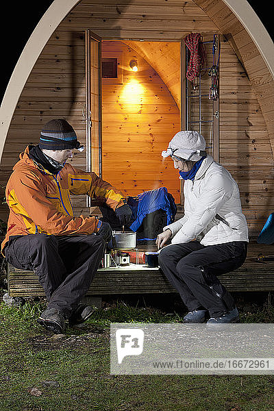 Ehepaar bei der Essenszubereitung vor einer Campingkapsel im Vereinigten Königreich
