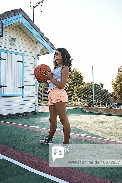 Ein Mädchen steht auf einem Basketballplatz und posiert für eine Kamera