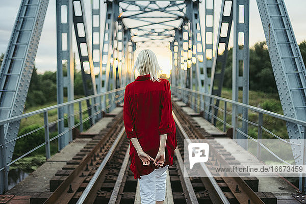 Frau im roten Hemd auf einer Eisenbahnbrücke stehend