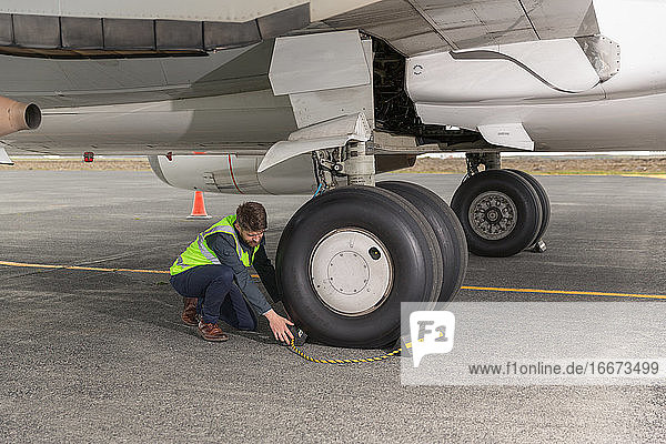 Männlicher Ingenieur beim Entfernen der Bremsen vom Flugzeugrad