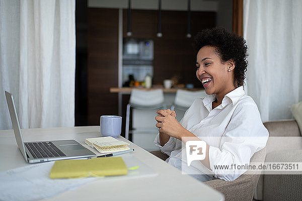 Glückliche gemischtrassige Geschäftsfrau während eines Online-Meetings