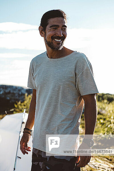 Mann schaut lächelnd weg an einem sonnigen Tag auf einem Campingplatz
