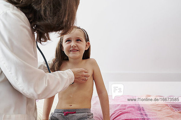 Kinderarzt untersucht kleines glückliches Mädchen mit Stethoskop. Chi