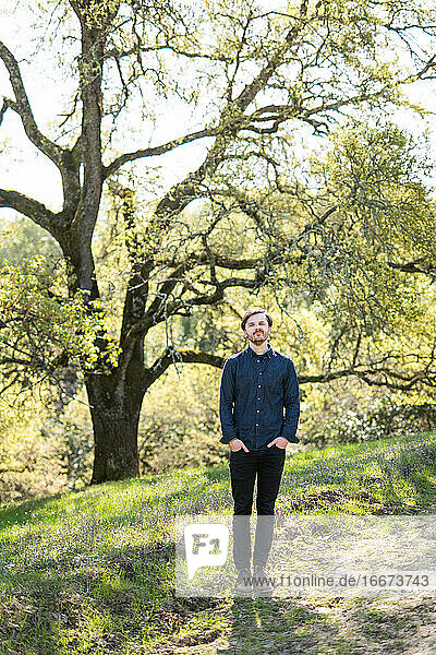 Full body portrait of man in casual clothes in front of Oak tree