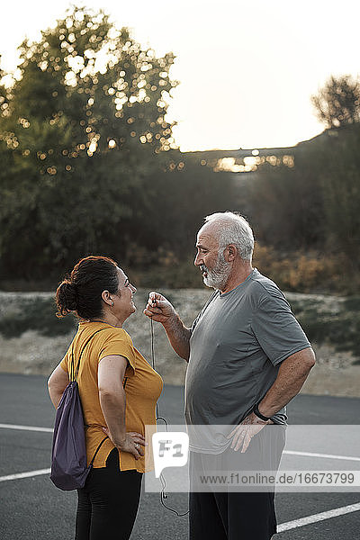 An elderly couple is sharing a headset for sport