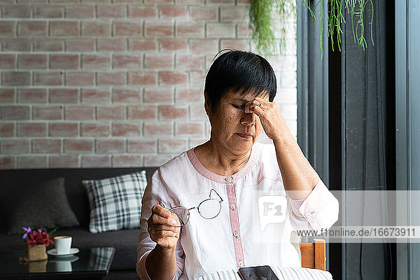 Alte Frau mit Kopfschmerzen bei der Nutzung eines Smartphones  Gesundheitskonzept