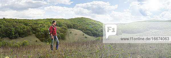 Erwachsener Mann blickt in die Ferne auf das Panorama eines bewaldeten Hügels
