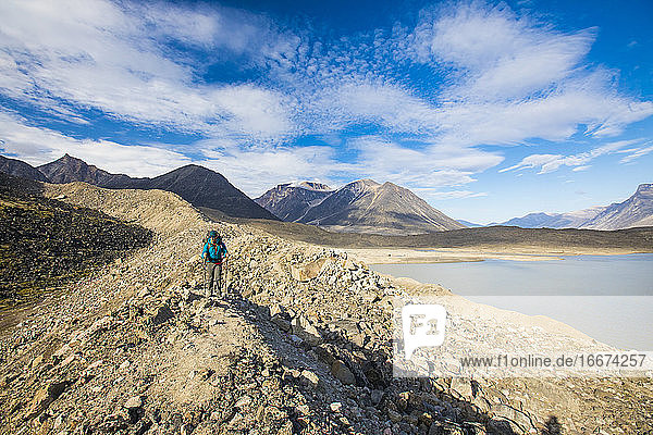 Rucksacktourist beim Wandern über eine felsige Gletschermoräne am Akshayak-Pass.