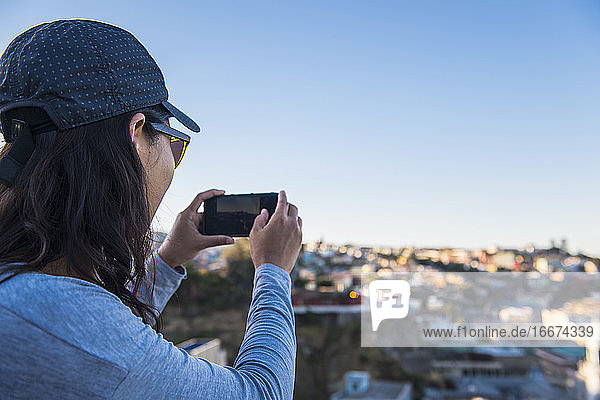 Woman taking photograph with smartphone  Valparaiso in Chile