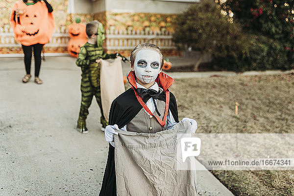 School aged boy dressed as Dracula Trick-or-Treating during Halloween