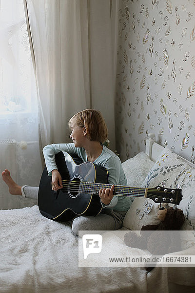 Das Mädchen spielt ein Musikinstrument und singt in einem hellen Raum.