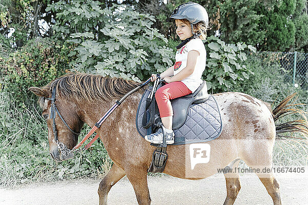 Glückliches Kind reitet Pferd auf der Koppel