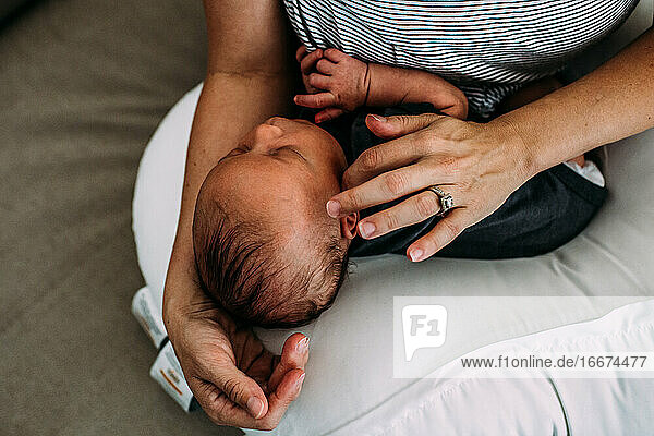 overhead of newborn baby napping in mothers arms