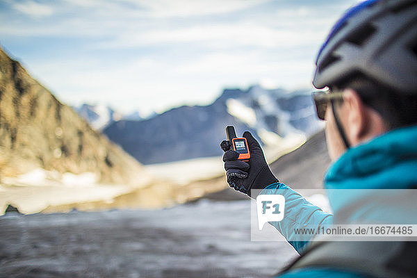 Ein Bergsteiger benutzt ein GPS  um auf einem hohen Bergpass zu navigieren.