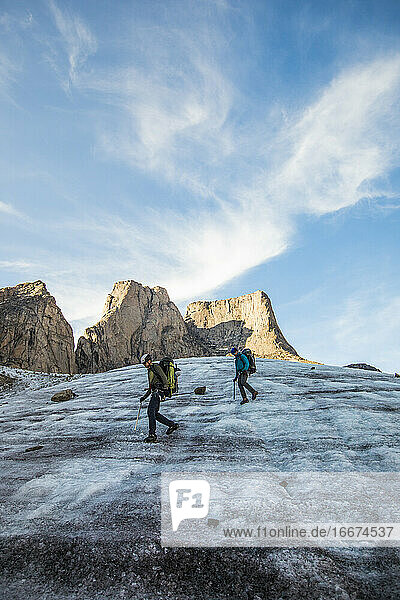 Zwei Bergsteiger überqueren einen Gletscher unterhalb des Berges Asgard.