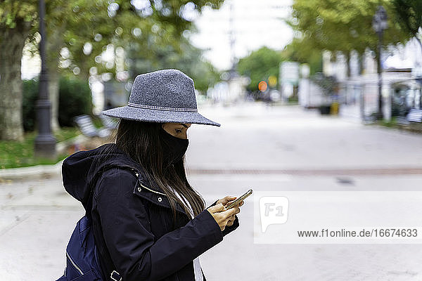 Schöne junge Frau steht auf der Straße und benutzt ihr Handy