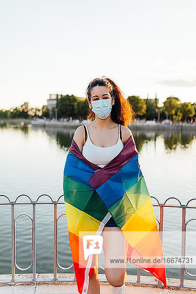 Junge Frau feiert Homosexuell Stolz Tag mit Maske und Regenbogen lgbt Flagge