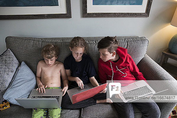 Geschwister arbeiten zu Hause mit Laptops gemeinsam am Fernunterricht