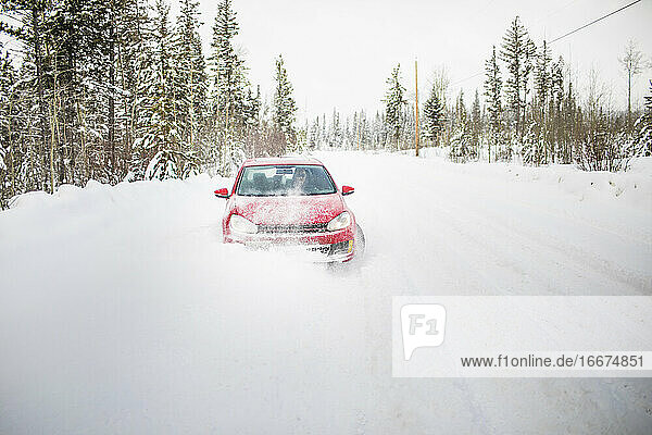 Vorderansicht eines roten Autos auf einer schneebedeckten Straße.