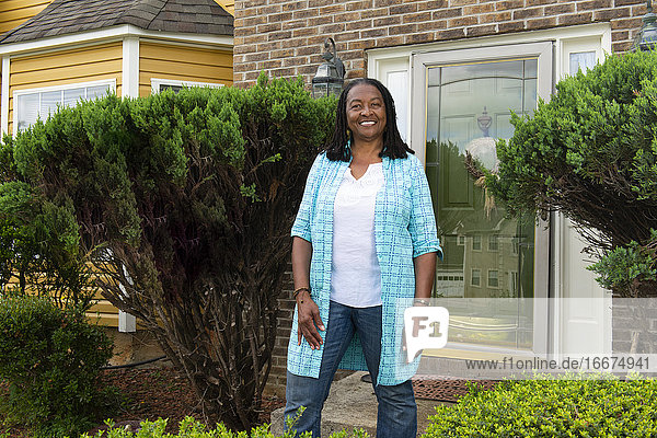 Smiling African-American woman standing in front of her house