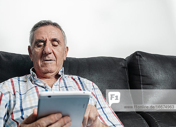 Älterer Mann mit Tablet auf dem Sofa