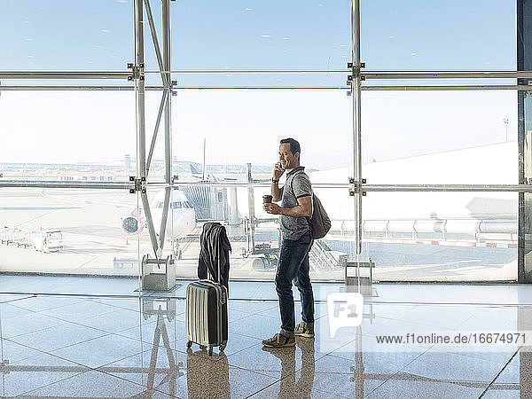 Junge Frau mit Koffer telefoniert beim Warten auf den Flug