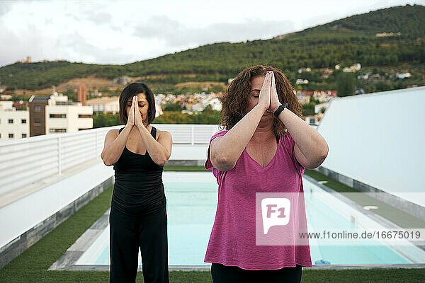 Frauen machen Yoga auf der Terrasse des Hauses  Namaste-Gruß
