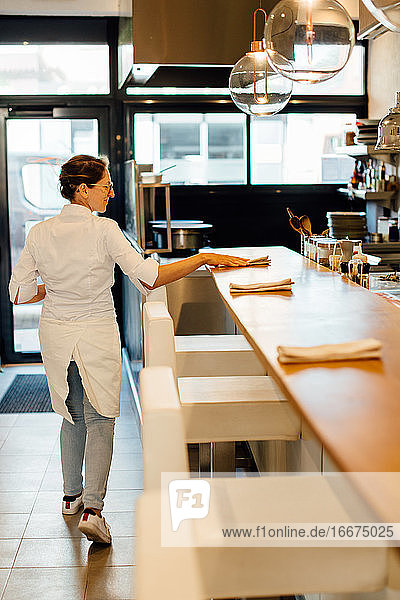 Eine Köchin legt Servietten auf die Theke in einem Restaurant mit offener Küche