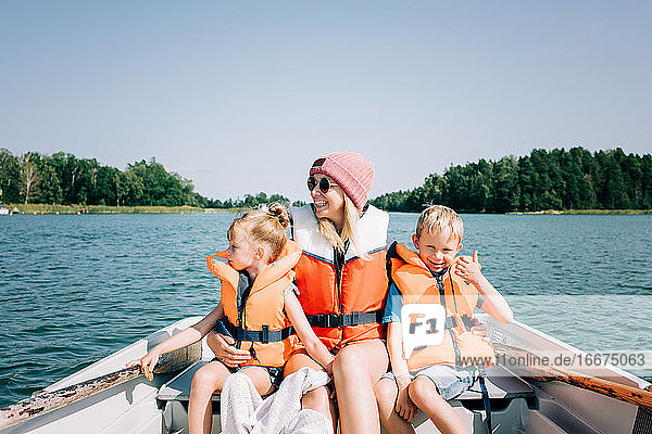 Mutter saß glücklich mit ihren Kindern auf einem Boot und genoss den Sommer in Schweden