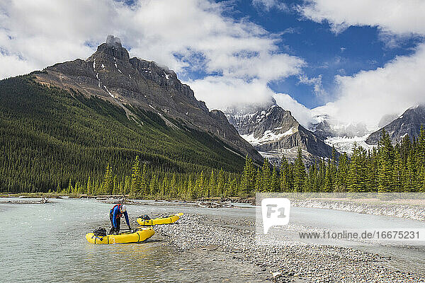 Ein Paddler bereitet sich darauf vor  sein gelbes Schlauchboot in den malerischen Fluss zu werfen.