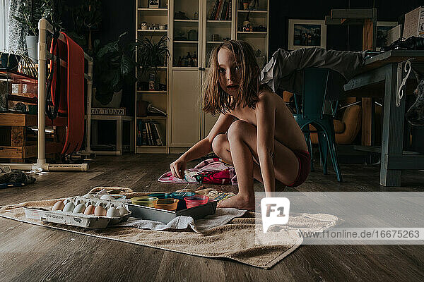 Junges Mädchen färbt Ostereier allein in einem Zimmer