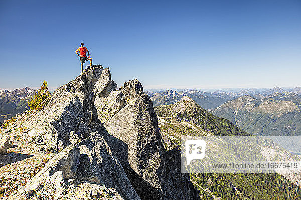Rucksacktourist steht nach einem langen Wandertag auf dem Gipfel eines Berges