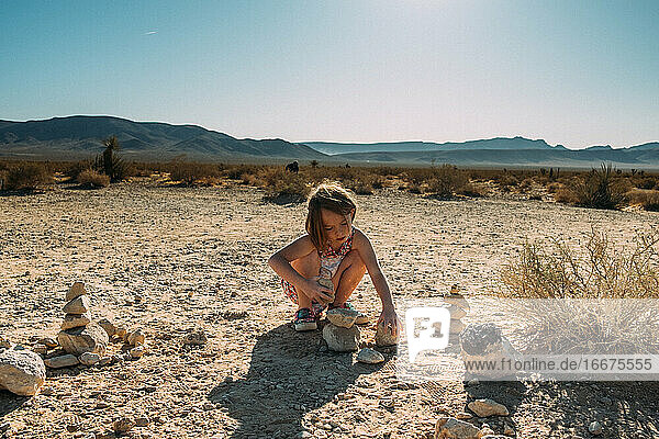 young girl building with rock in the desert