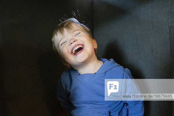 Fröhlich und glücklich Kleinkind Junge kippt den Kopf zurück  während lachen drinnen