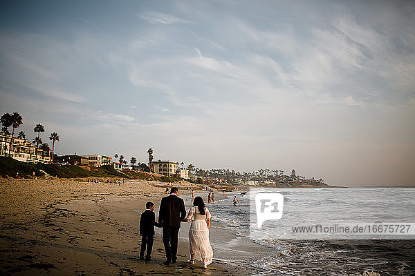 Frischvermählte und neunjähriger Sohn spazieren am Strand in San Diego