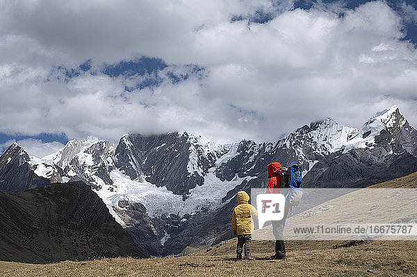 A mom and her son hiking along the Huayhuash Circuit at high mountains