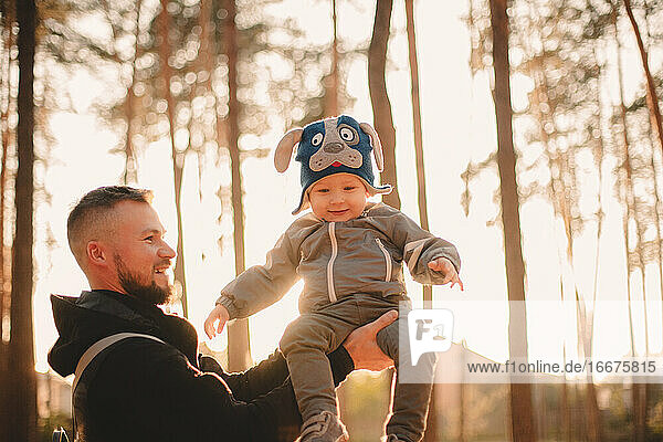 Glücklicher Vater spielt mit seinem Sohn draußen im Park an einem sonnigen Tag