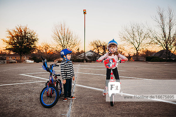 Junge Schwester und Bruder fahren zusammen Fahrrad auf einem leeren Parkplatz