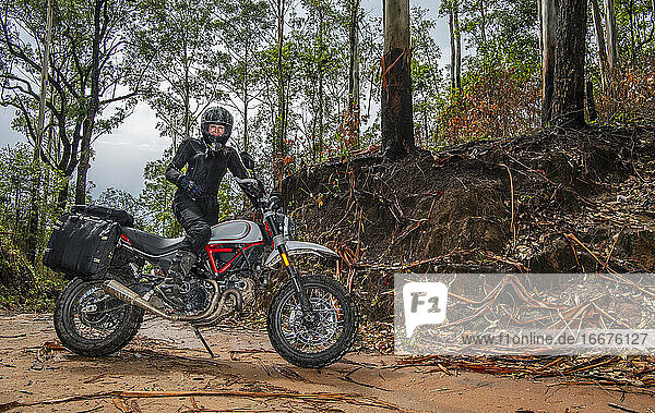 Frau posiert auf ihrem Scrambler-Motorrad im thailändischen Wald