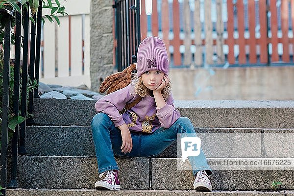 Porträt eines jungen Mädchens  das auf einer Stufe sitzt und wartet